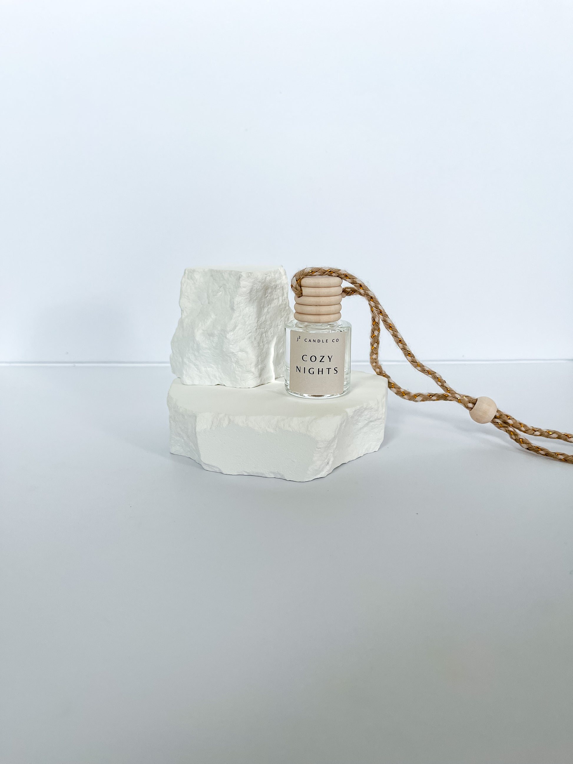 Small bottle labeled 'Cozy Nights' on a white stone surface with a white background