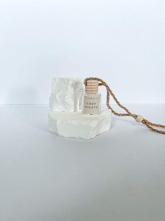 Small bottle labeled 'Cozy Nights' on a white stone surface with a white background